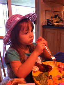 Maddo, her plate full, eyeballs what her sister has across the dinner table.